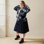 Smokey Unisex Hoodie for Stylish Streetwear Enthusiasts worn with a pleated skirt, showcasing an urban fashion look.