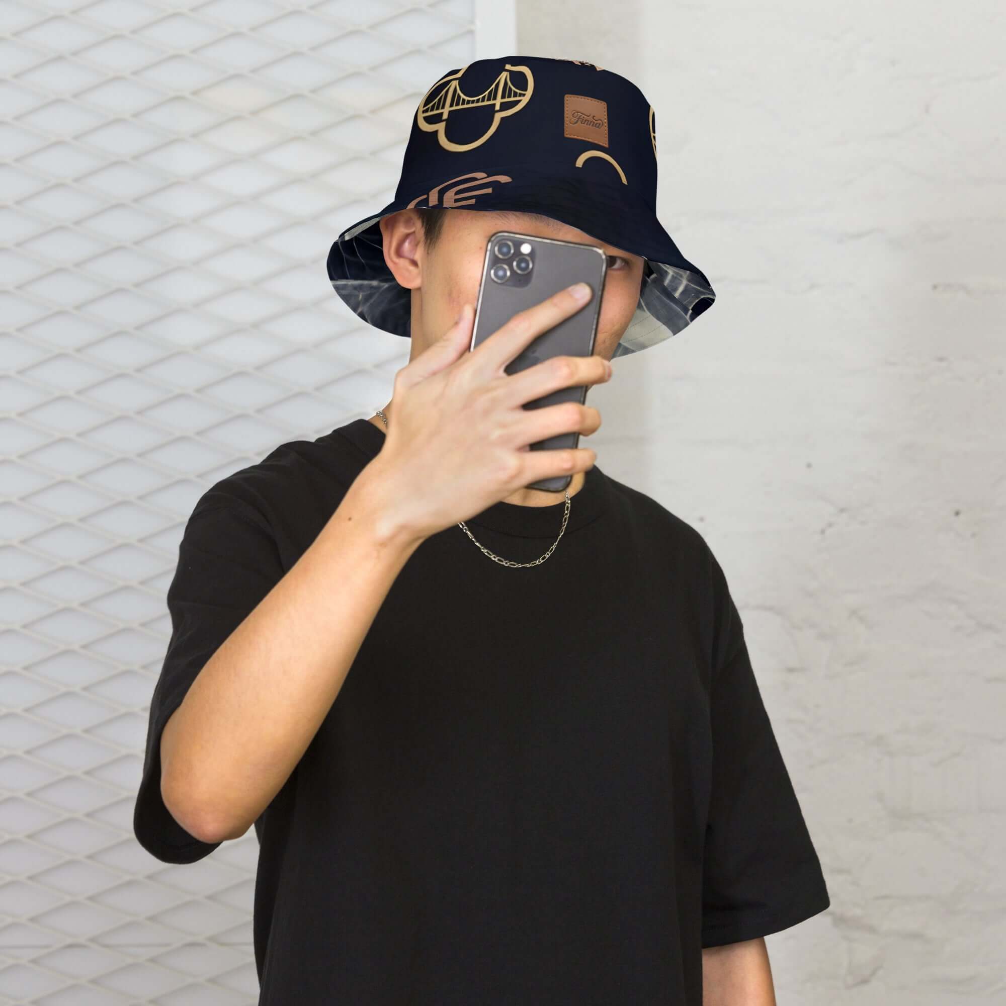 Young person wearing a reversible bucket hat streetwear and taking a selfie in an urban setting.