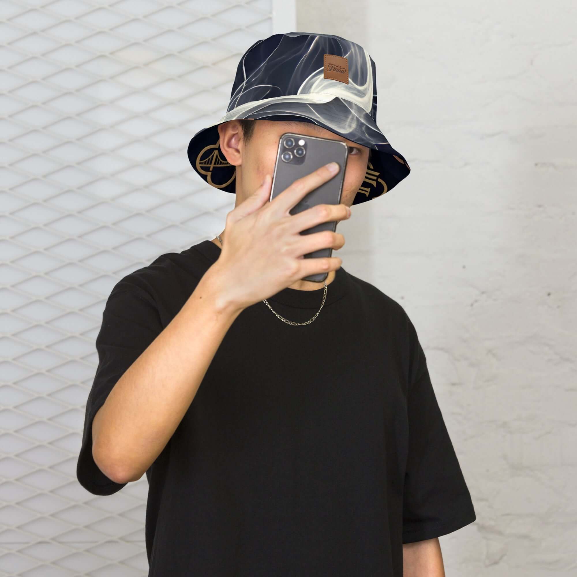 Person wearing a reversible bucket hat streetwear, showcasing two styles while holding a phone.