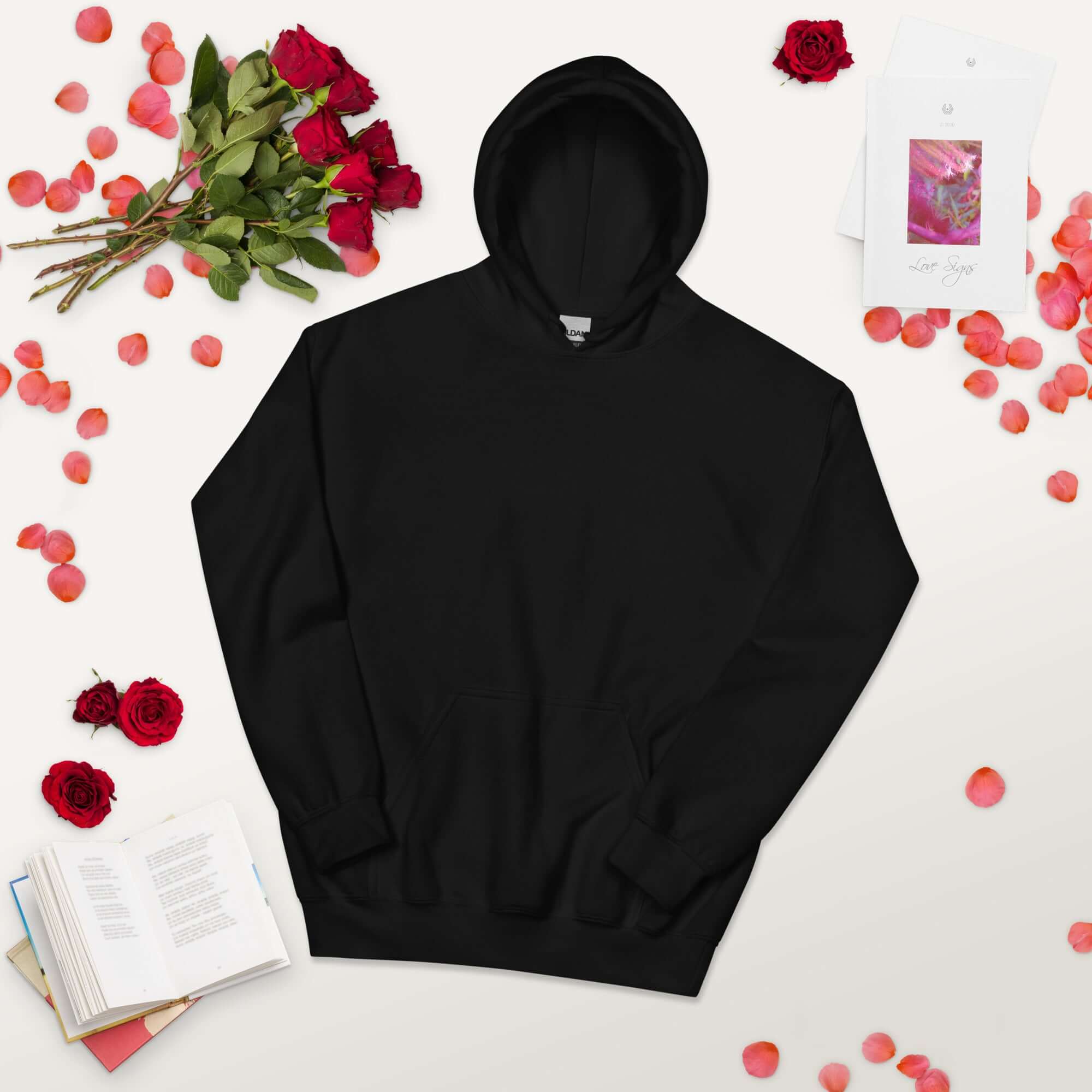 Lynxdonk Unisex Hoodie Cozy and Stylish Essential black hoodie displayed with roses and books on a light background.
