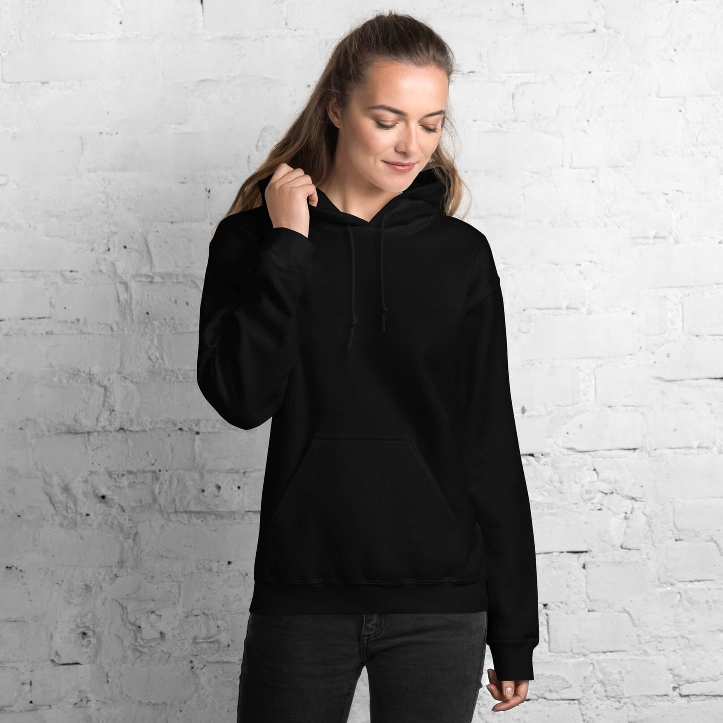 Model wearing Lynxdonk Unisex Hoodie Cozy and Stylish Essential in black against a white brick background.