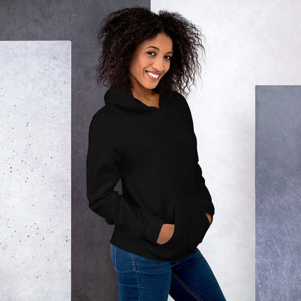 Lynxdonk Unisex Hoodie Cozy and Stylish Essential worn by woman with curly hair, showcasing a black hoodie in a modern setting.