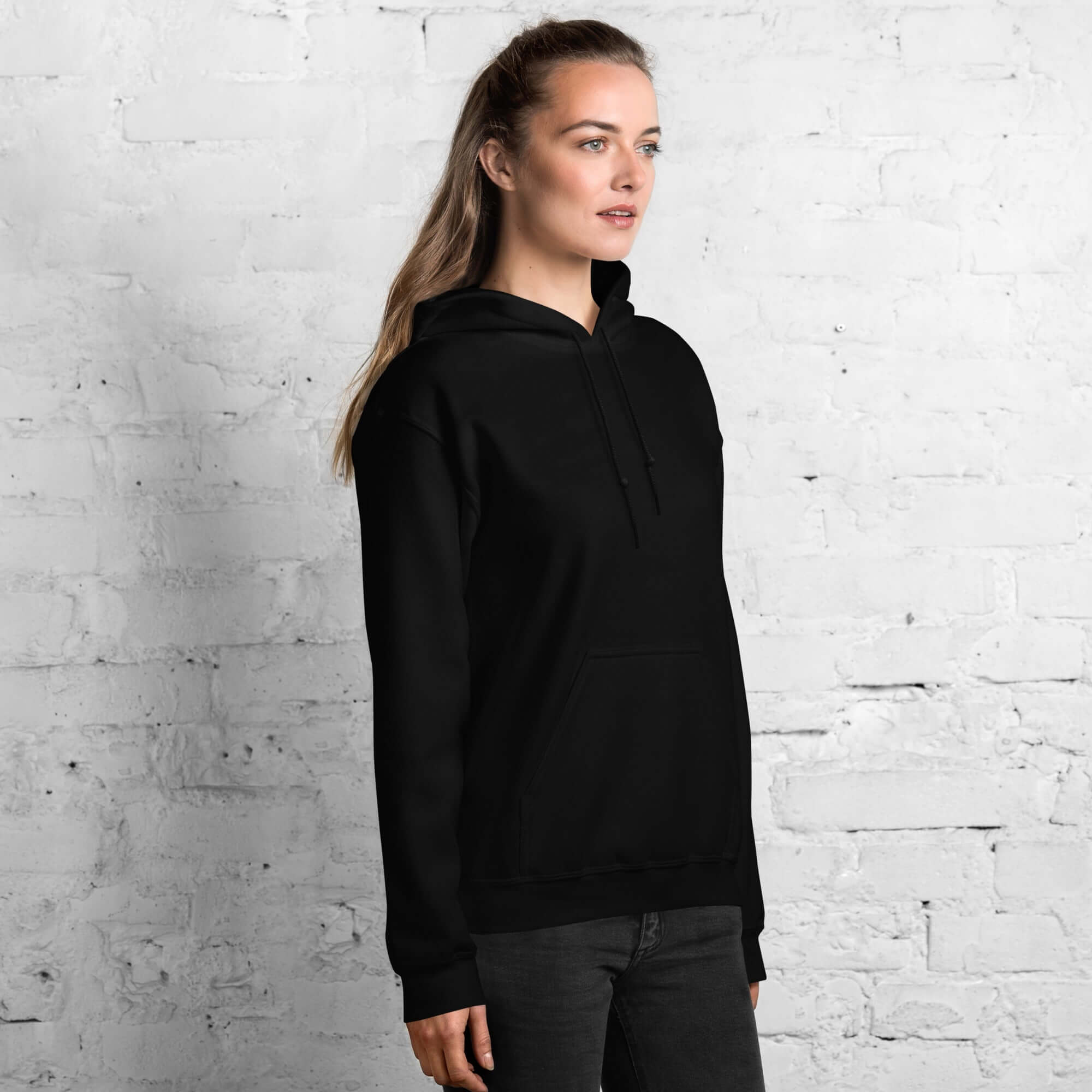 Lynxdonk Unisex Hoodie Cozy and Stylish Essential in black worn by a model against a brick wall.